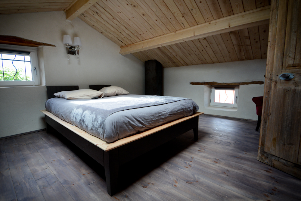 Grand lit sous charpente en bois